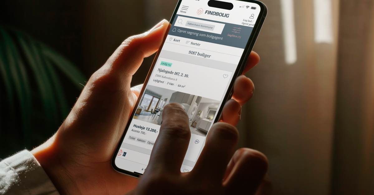 A person holds a smartphone displaying a real estate app 